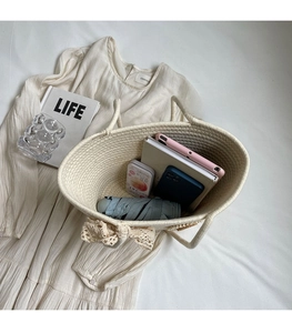 Detail shot of the spacious interior of a woven tote bag with a lace bow on a beige dress
