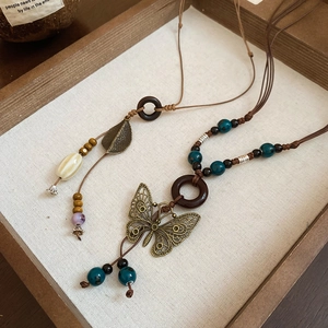 Detail of vintage ceramic necklace with hollow butterfly pendant and wooden beads