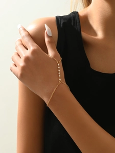 Detail of golden finger bracelet chain with elegant pearl accents on model hand
