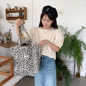 Close-up of leopard print canvas tote bag featuring black and white pattern and textile label