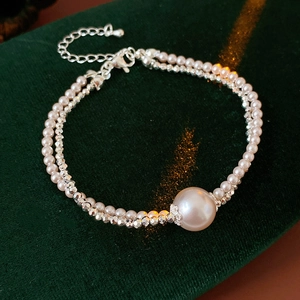 Detail of silver beaded and white pearl double-layer bracelet on green velvet