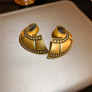 Detailed macro view of vintage gold fan earrings with blue resin stones and black lines