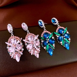 Detail of pink and blue crystal teardrop earrings on a dark leather background