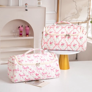 Close-up of quilted floral cosmetic bags with pink bow patterns and sturdy top handles