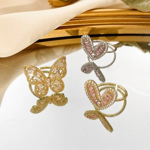 Close-up of adjustable gold butterfly and pink heart rings with zircon on mirror