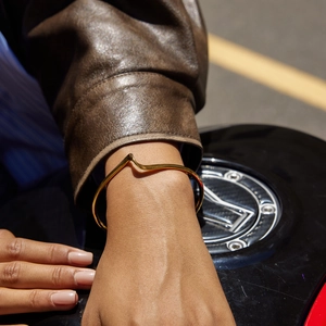 Détail d'un bracelet jonc vague en acier inoxydable plaqué or 18k au poignet d'une femme