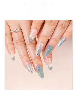 Detail of sage green cat-eye almond press-on nails with 3D floral and butterfly art