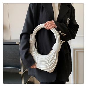 Detail of white knot texture handbag with metallic accents held by fashion model