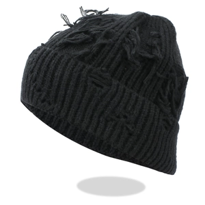 Close-up of distressed black knit beanie showing detailed ripped holes and fringe texture