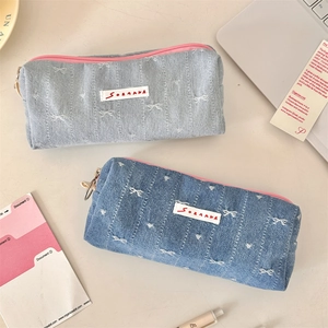 Close-up of denim pencil cases with pink metal zippers and white bow embroidery