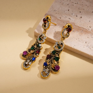 Détail macro de boucles d'oreilles dorées vintage avec strass colorés sur pierre naturelle