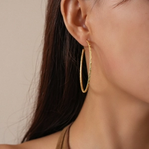 Detailed close-up of matte gold textured hoop earrings worn for a minimalist chic style
