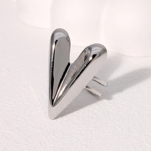 Minimalist silver heart shaped polished stainless steel ring on white textured surface
