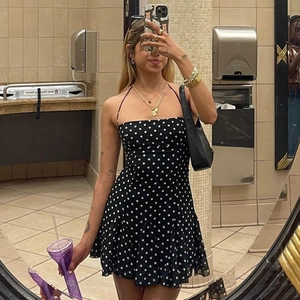 Detail of black polka dot mini dress featuring ruffled hem and slim spaghetti straps