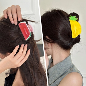 Detail of watermelon and pineapple hair claws shown on a ponytail for hair styling