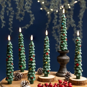 Set of green Christmas tree LED candles on wooden tray with festive warm lighting