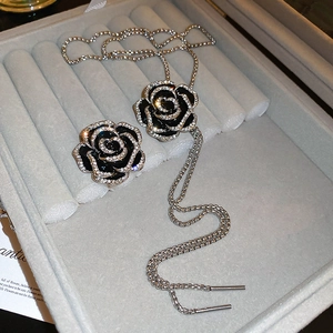 Détail d'un ensemble de bijoux camélia en émail noir et zircons dans un coffret cadeau