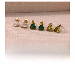 Macro shot of triangle cut crystal stud earrings in emerald and clear titanium steel