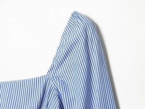 Détail de près du tissu à rayures bleues et blanches avec col carré et manche bouffante