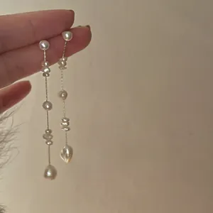 Detail of French chic baroque freshwater pearl tassel earrings held by hand
