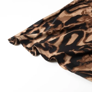 Detailed close-up of leopard print satin fabric with fine stitching on the skirt hem