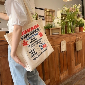 Detailed side view of the large capacity canvas tote bag worn on shoulder in a cafe setting