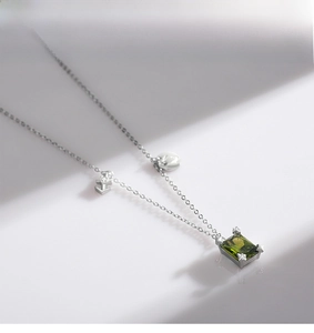 Close-up of S925 silver necklace with emerald-cut green stone and geometric pendants