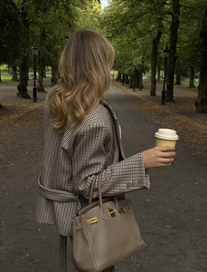 Close-up of houndstooth plaid blazer paired with a vintage brown leather handbag