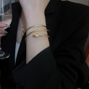 Detailed close-up of golden snake spiral arm cuff bracelet with scaled metal texture