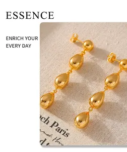 Macro detail of cascading gold teardrop earrings on elegant French vintage fabric