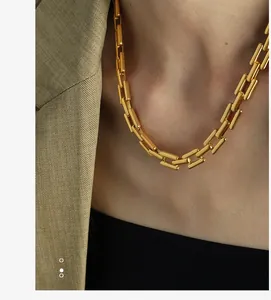 Detail of chunky gold chain link necklace worn with a chic beige blazer on model