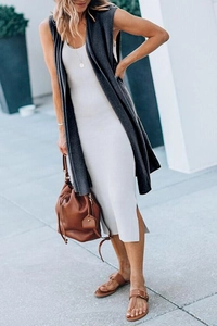 Straßenstil-Aufnahme einer langen grauen ärmellosen Weste über einem weißen Strickkleid
