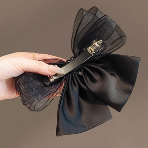 Elegant black large mesh bow hair clip with a metal spring fastener held in hand