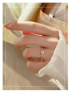 Detailed view of an elegant gold ring with round cut moissanite worn by a model