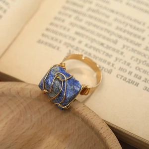 Détail d'une bague artisanale en lapis-lazuli brut avec fil doré sur un livre ancien