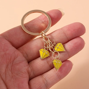 Fashionable gold-plated keychain with yellow enamel diamond charms held in hand