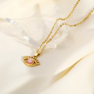 Elegant gold evil eye necklace with pink gemstone pendant on silk background