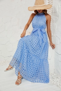 Detail of light blue halter maxi dress showing checkered texture and tie-waist in resort style