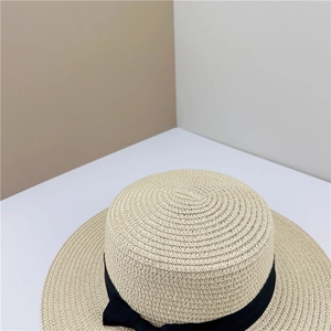 Détail d'un chapeau de paille canotier plat avec texture tissée et ruban noir élégant