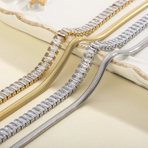 Detail of gold and silver flat snake chains paired with rectangular crystal tennis chains