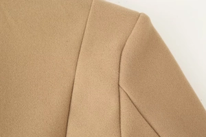 Detailed close-up showing the camel wool fabric texture and shoulder stitching of the coat