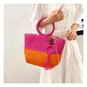 Detail of pink and orange straw bag with wooden beads, tassels and round top handle