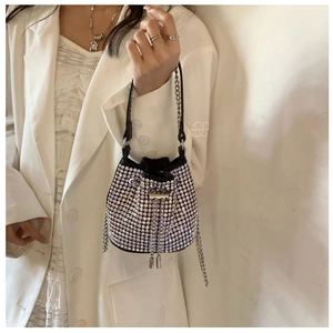 Sparkling black bucket bag with silver rhinestones held by a model in a white blazer