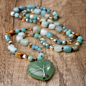 Detail of handmade heart-shaped green stone pendant with wire-wrapped tree of life