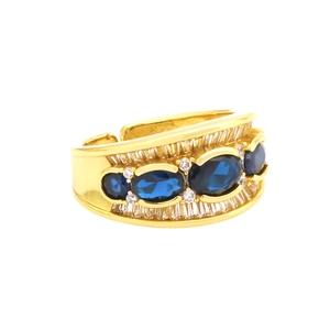 Close-up of gold plated X-shaped ring with dark blue stones and pavé set zircons