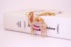 Detailed close-up of a sparkling crystal-studded golden camel keychain on a book