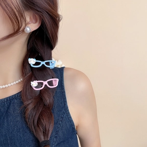 Detail shot of cute cat character sunglasses hair clip worn on model's braided hair