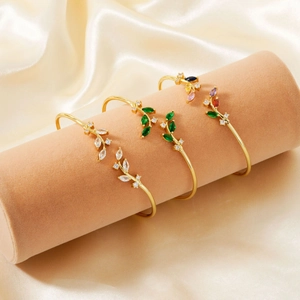Detail of leaf design open bangles with colorful marquise-cut gems on satin fabric