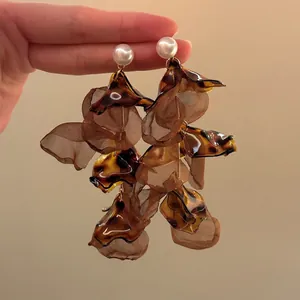 Close-up of leopard tortoise shell resin earrings with pearl studs and brown mesh petals