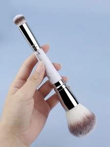 Close-up of dual-ended makeup brush with white marble handle and silver metal ferrule